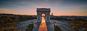 Sunrise view of the Arc de Triomphe in Paris with golden light illuminating the Champs-Élysées