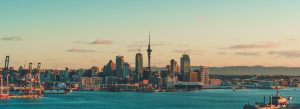 Auckland skyline at sunset with Sky Tower, waterfront harbor, and city buildings in New Zealand