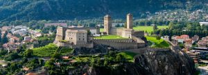 Panoramic view of Castelgrande fortress overlooking Bellinzona with green hills and historic stone towers