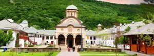 Central church and courtyard at Cozia Monastery surrounded by green hills in Romania