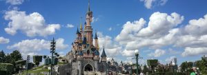 Disneyland Paris Sleeping Beauty Castle with colorful towers under a bright blue sky and clouds