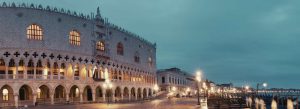 Evening view of Doge's Palace along the waterfront near St. Mark's Square with illuminated arches and streetlights