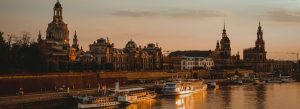 Sunset view of Dresden skyline with Frauenkirche, historic buildings, and boats on the Elbe River
