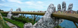 Golden Bridge held by giant stone hands in Ba Na Hills Da Nang Vietnam with tourists walking