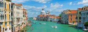 Grand Canal in Venice with gondolas and boats passing historic palaces and the domed Basilica di Santa Maria della Salute