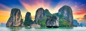 Limestone karsts and cruise boat in Ha Long Bay Vietnam during colorful sunset