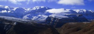 High Atlas Mountains covered with snow and clouds under blue sky in Morocco