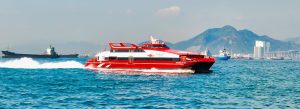 High-speed ferry traveling between Hong Kong and Macau across the South China Sea with skyline and mountains in the background