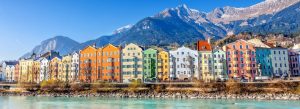 Colorful houses along the Inn River in Innsbruck with the Austrian Alps in the background