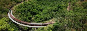 Scenic train crossing a curved bridge through rainforest on the Kuranda Scenic Railway
