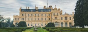 Neo-Gothic Lednice Chateau with manicured gardens and hedges under a cloudy sky