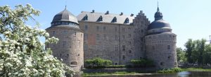 Örebro Castle surrounded by blooming trees beside a river on a sunny spring day