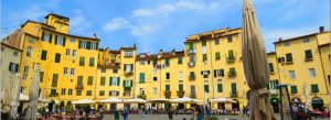 Colorful historic buildings in Piazza dell'Anfiteatro with outdoor cafés and people enjoying the square