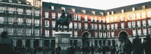 Equestrian statue of Philip III of Spain in Plaza Mayor surrounded by historic red buildings and a lively crowd