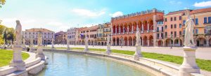 Statues lining the canal in Prato della Valle with historic buildings and Palazzo della Ragione in Padua