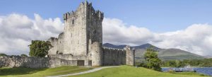Ross Castle overlooking Lough Leane with mountains in the background on a sunny day