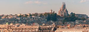Panoramic view of Paris skyline with the white domes of Sacré-Cœur Basilica rising above Montmartre at sunset