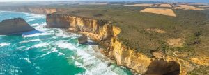 Aerial view of the rugged limestone cliffs and turquoise waters along the Great Ocean Road coastline in Victoria, featuring dramatic sea stacks near the Twelve Apostles.