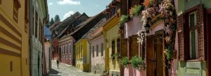 Colorful cobblestone street with pastel houses and flower balconies in Sighișoara Citadel, Transylvania, Romania