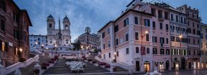 Spanish Steps at dawn with blooming flowers leading up to Trinità dei Monti under a dramatic blue sky