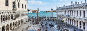 Tourists walking in St. Mark’s Square with historic buildings and lagoon view