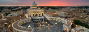 Aerial view of St. Peter’s Basilica and St. Peter’s Square at sunset with illuminated colonnades