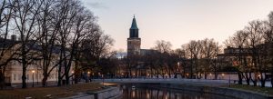 Riverside view at sunset with historic cathedral tower, bridge, and trees in a peaceful European city