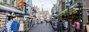 Busy shopping street in Volendam with souvenir shops, colorful displays, and visitors strolling through the historic village center