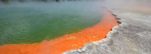 Champagne Pool geothermal area with vibrant orange mineral edge and steaming green water in Wai-O-Tapu, New Zealand