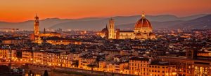 Sunset skyline of Florence featuring the illuminated Florence Cathedral and historic buildings along the Arno River