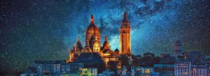Night view of Sacré-Cœur Basilica illuminated under a starry sky overlooking the Paris skyline