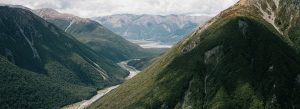 Scenic view of the Southern Alps in Arthur’s Pass National Park with lush green valleys and winding river, New Zealand