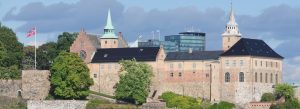 Historic Akershus Fortress in Oslo, Norway, with medieval stone walls, castle towers, and the Norwegian flag overlooking the city.