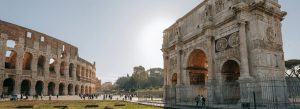 Ancient Arch of Constantine beside the Colosseum in Rome, Italy under a bright blue sky.