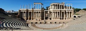 Ancient Roman theater and amphitheater ruins at the Archaeological Ensemble of Mérida in Spain under a clear blue sky.