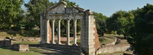 Ancient ruins and restored columns at the archaeological site of Apollonia in Albania surrounded by greenery.