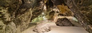 Interior view of Areni-1 Cave in Armenia featuring ancient rock formations and illuminated walking paths.
