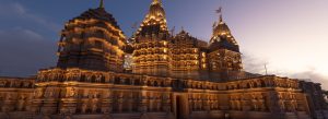 BAPS Hindu Mandir Abu Dhabi illuminated at dusk with intricate carvings and golden lighting