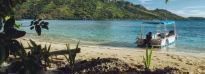 Tropical beach in Fiji with white sand turquoise water and boat anchored near shore