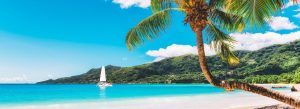 Beau Vallon Beach on Mahé Island in Seychelles with palm trees, turquoise water, and a sailing yacht