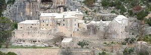 Historic stone buildings of Blaca Hermitage nestled beneath rocky cliffs on Brač Island in Croatia.