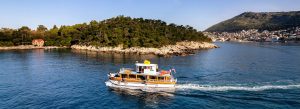 Tourist boat sailing near Lokrum Island off the coast of Dubrovnik, Croatia during a sunny Adriatic Sea cruise.