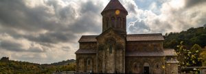 Bodbe Monastery in Georgia surrounded by green hills under dramatic cloudy skies