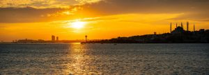Golden sunset over the Bosphorus Strait with Istanbul skyline and mosque silhouettes in Turkey.