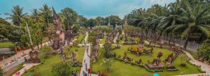Panoramic view of Buddha Park in Vientiane, Laos featuring large Buddhist and Hindu sculptures surrounded by tropical gardens