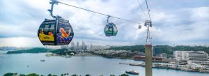 Colorful Singapore cable cars with Pokémon theme gliding above Sentosa Island and HarbourFront skyline
