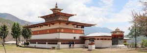 Traditional Bhutanese temple Chhimi Lhakhang in Punakha Valley surrounded by mountains and open landscape.