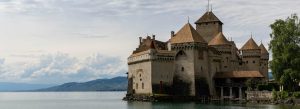 Historic Chillon Castle on the shores of Lake Geneva with mountains and cloudy skies in Switzerland