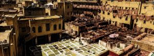 Traditional leather dyeing vats at Chouara Tannery in Fes, Morocco viewed from above.