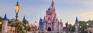 Cinderella Castle at Magic Kingdom in Walt Disney World Resort during sunset with glowing lights and floral landscaping.
